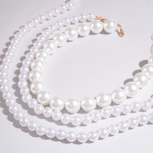 Detailed view of triple-layered white pearl necklace with adjustable gold metal clasp