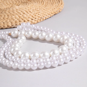 Detail of multi-layered faux pearl necklace with gold clasp on a neutral background