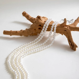 Macro view of multi-layer white pearl necklace draped over a rustic wooden branch