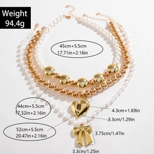 Detalle del collar de perlas multicapa con colgantes de lazo dorado y corazón hueco