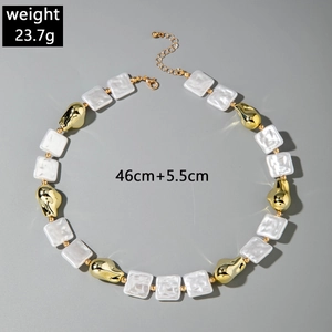 Detalle de collar multicapa con cuentas blancas texturizadas y detalles dorados