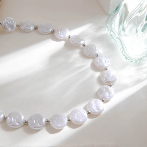 Close-up of elegant cream beaded necklace with textured faux pearls and silver spacers