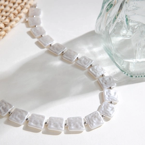 Detail of square hammered pearl beads and silver spacers on a minimalist layered necklace