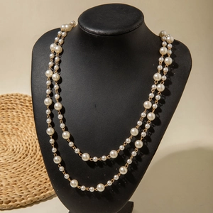 Detail of layered imitation pearl necklace with gold-tone alloy chain on a display stand