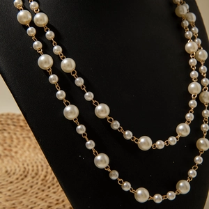 Detail of double-layer faux pearl necklace with gold chain on a jewelry display stand