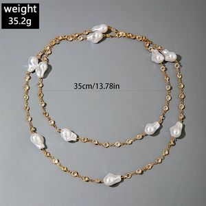 Detail view of layered gold chain necklace with baroque pearls and faceted gemstones