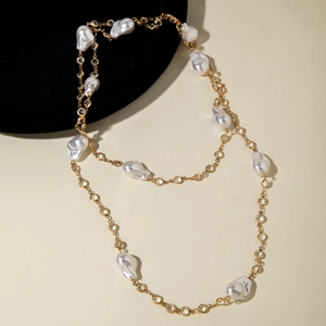 Close-up of golden chain necklace with baroque pearls and transparent crystals