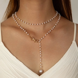 Detail view of double-layered faux pearl necklace with gold bow and drop pearl pendant