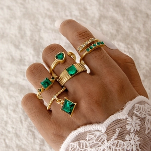 Gros plan d'un ensemble de bagues vintage dorées avec gemmes émeraude et strass
