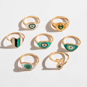 Détail d'un lot de 7 bagues dorées avec motifs œil protecteur et cœurs émail vert émeraude