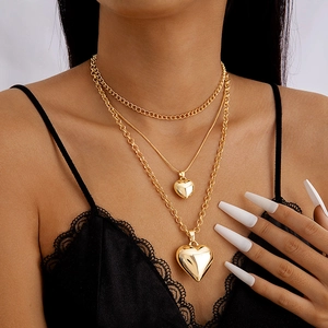 Detail of layered gold chunky chain necklace with heart pendants on a model