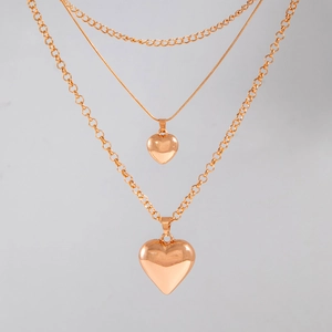 Detailed close-up of triple-layered rose gold chain necklace with heart pendants