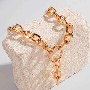 Detail of chunky gold aluminum multi-layer chain necklace on natural stone display