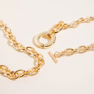 Detail of chunky gold chain necklace with toggle clasp showing polished finish