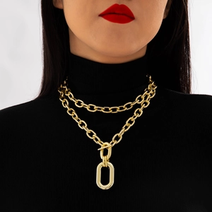 Close-up of double-layer gold chain necklace with chunky oval pendant and T-bar toggle clasp