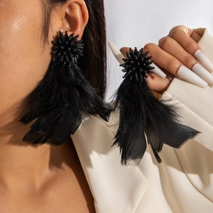 Detail view of dramatic black feather drop earrings with beaded semi-sphere top and tassel