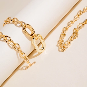 Detail of chunky gold chain necklace with toggle clasp and polished metal finish