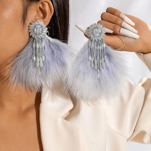 Detail view of light blue beaded tassel earrings with soft feathers on a model