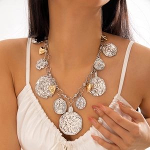 Close-up of layered chunky aluminum chain with hammered silver coins and gold heart charms