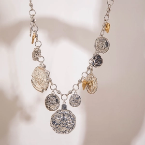 Detail of vintage silver acrylic necklace featuring hammered coins and floral pendants