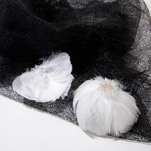Close-up of white feather earrings with iridescent beads and crystals on black mesh