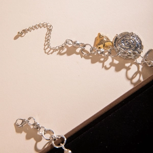 Detail of layered gold heart and silver disc charms on mixed metal aluminum chain