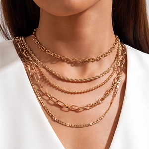 Detail of five-layer layered gold necklace set with varying chain styles and textures