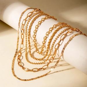 Detail showing various layered golden chains with paperclip and rope chain textures