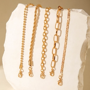 Detail of five-piece gold chain bracelet set with bead and cable links on stones