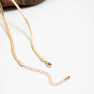 Close-up of golden snake chain necklace with lobster clasp and adjustable extension chain