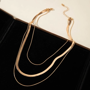 Detailed view of layered gold snake chains with lobster clasp and adjustable closure