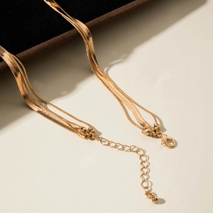 Close-up of gold layered chain necklace featuring flat snake links and lobster clasp