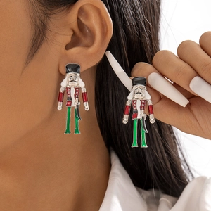 Boucles d'oreilles casse-noisette émaillées rouge et vert portées par un modèle