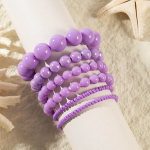 Handmade purple resin bead bracelet set displayed on beach sand with a starfish decoration