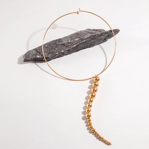 Minimalist gold metal choker necklace with graduated bead pendants on natural stone