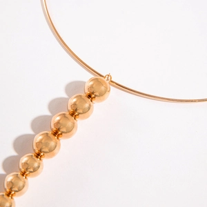 Punk style gold torque choker necklace with polished metal beads on white background