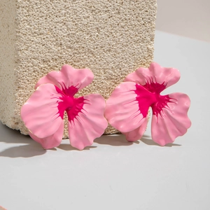 Detailed view of 3D pink enamel petal earrings on a stone display pedestal