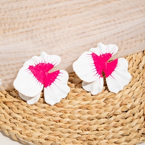 Macro detail of large floral earrings featuring layered white petals and magenta centers