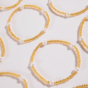Ensemble de 12 bracelets tendance avec perles dorées et perles blanches sur fond blanc