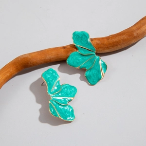 Macro detail of green enamel petal earrings with gold metallic swirling textures