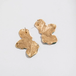 Macro detail of gold petal earrings showing hammered texture and metal leaf craftsmanship
