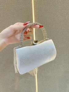 Detail of silver evening clutch bag featuring rhinestone tassels and round metal handle