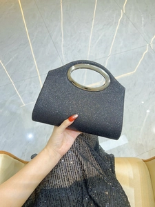 Detail of black glitter evening clutch featuring a large silver metal ring handle
