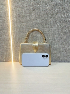 Detail of luxury gold snake pattern clutch bag with leaf clasp and metal handle