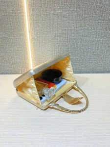 Internal view of gold evening clutch showing capacity for phone, perfume and lipstick