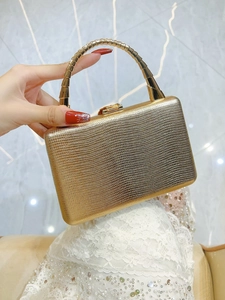 Detail of luxury gold snakeskin clutch bag with structured metal handle and snap closure