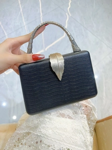 Detail of luxury black lizard pattern clutch featuring elegant gold leaf lock and metal handle