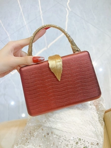 Detailed view of luxury snakeskin clutch with golden leaf clasp and bamboo handle