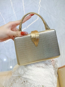 Detail of luxury gold snake pattern clutch with leaf clasp and metal handle