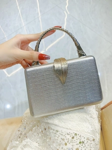 Detail of silver evening clutch with snake texture and golden leaf-shaped clasp